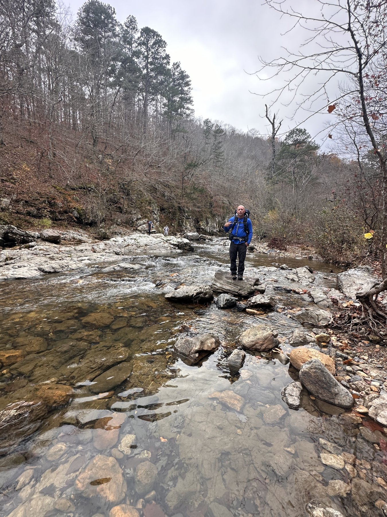 Hiker in the distance crossing a shallow rocky creek